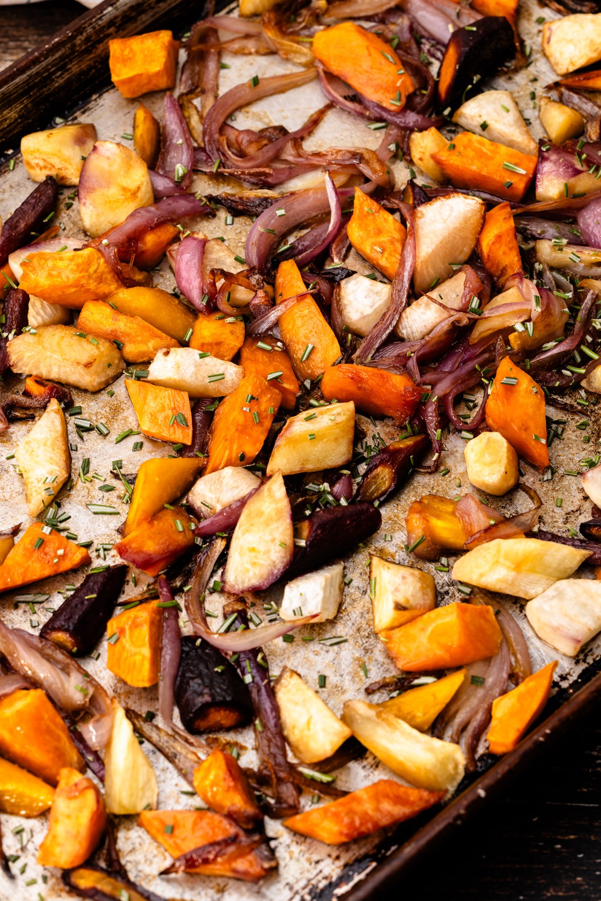 A sheet pan of roasted vegetables sprinkled with chopped rosemary for Balsamic Roasted Root Vegetables.