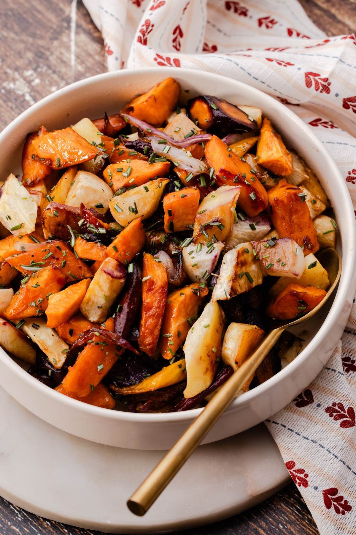 A serving bowl of Balsamic Roasted Root Vegetables, sprinkled with chopped rosemary.