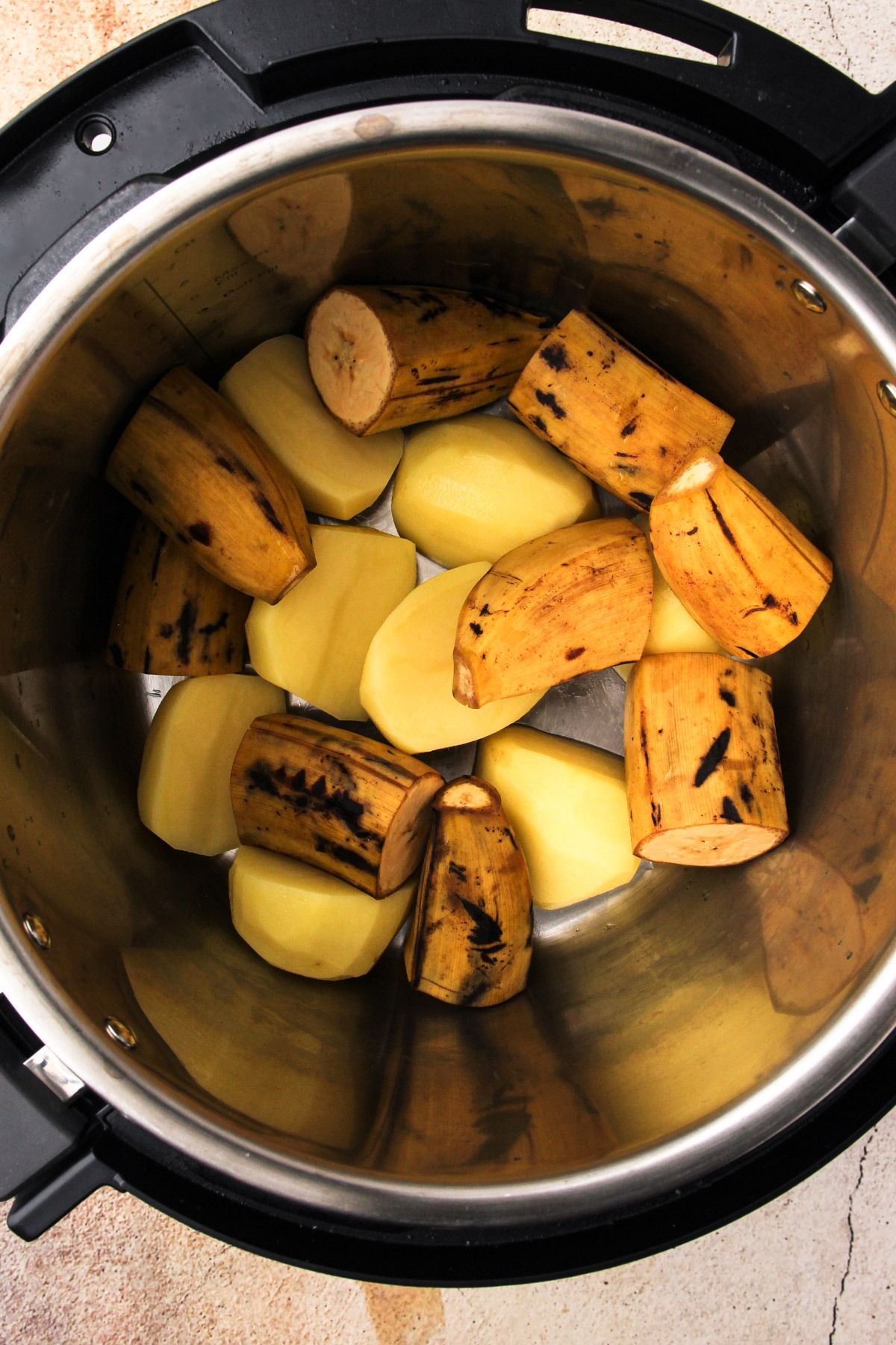 Cut potatoes and ripe plantains in an instant pot for sudado de pollo.