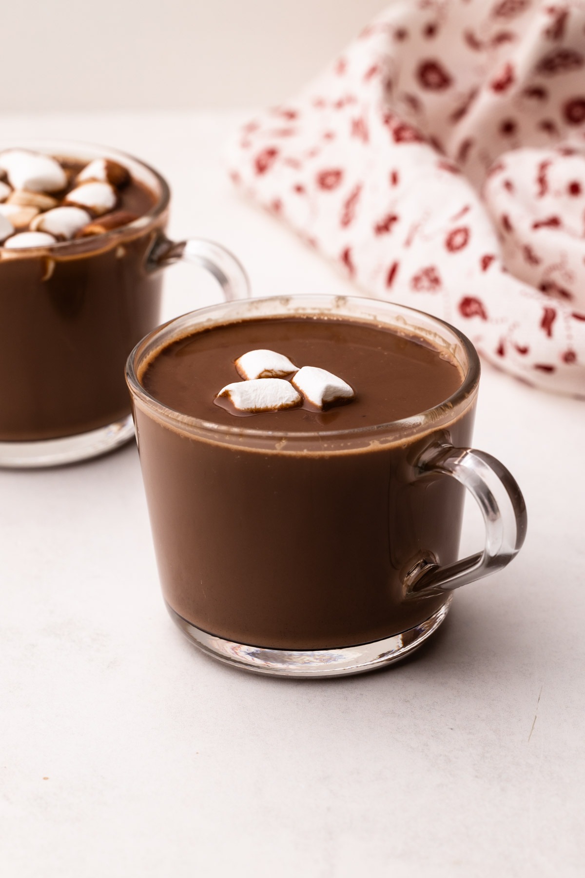A mug of hot chocolate with chocolate chips with marshmallows on top.