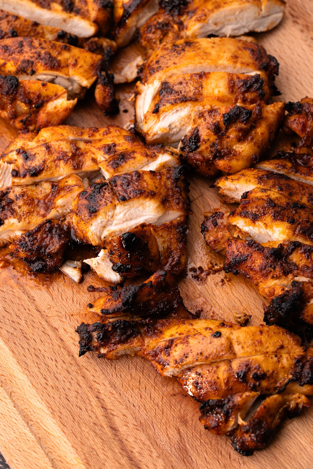 Sliced air fryer chicken thighs on a cutting board.