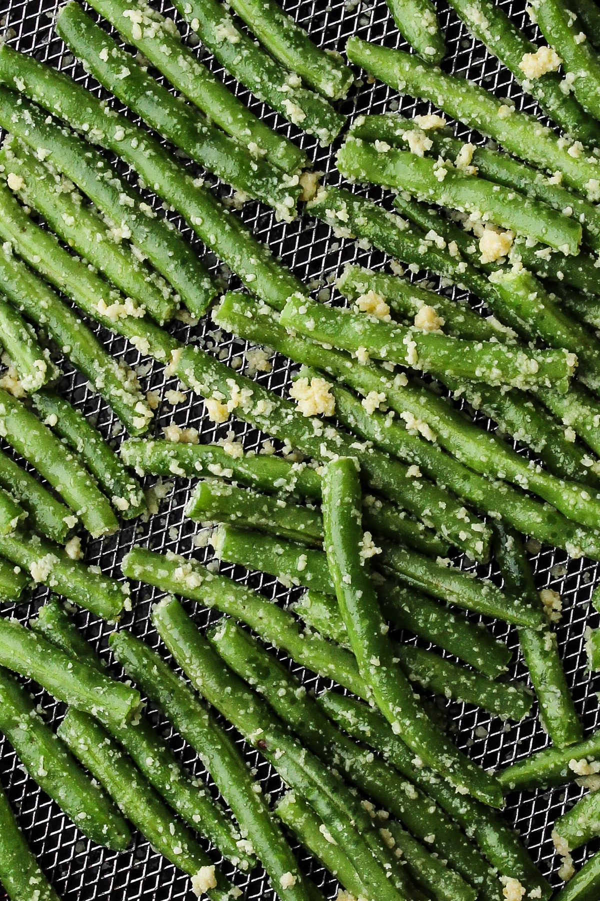 Prepped green beans in an air fryer basket.