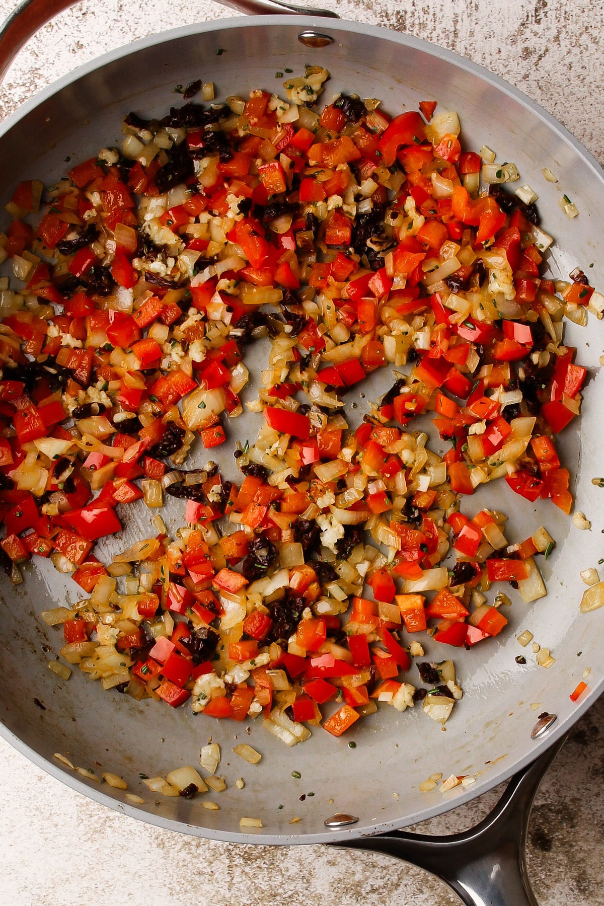 Sundried tomatoes, and italian sofrito cooking in a skillet.