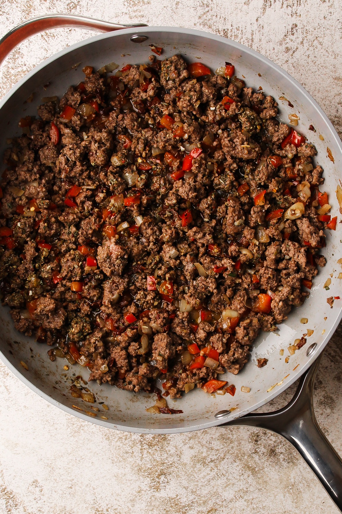 Ground beef cooking in a skillet with Italian sofrito.