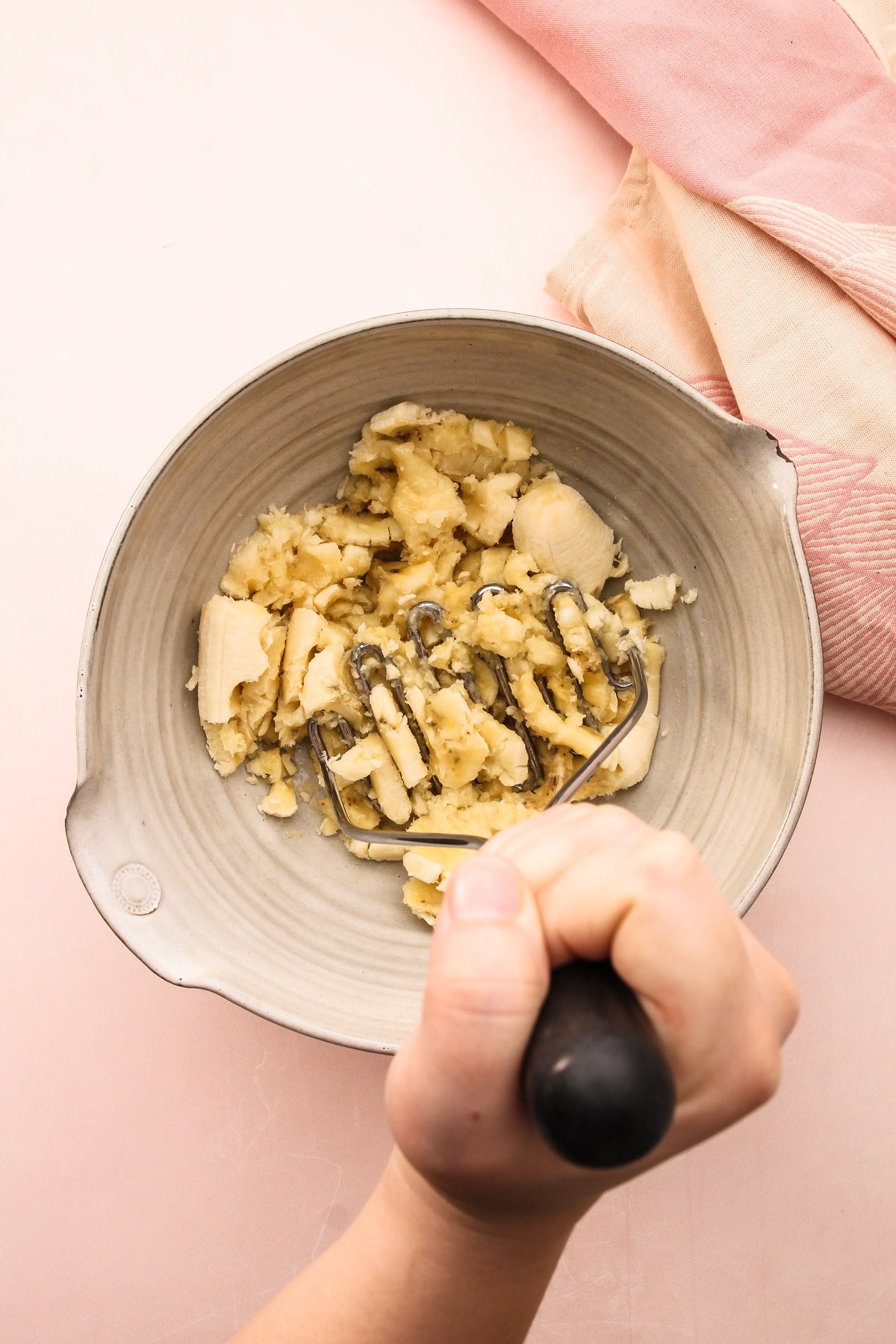 Mashing bananas in a bowl for banana bread.