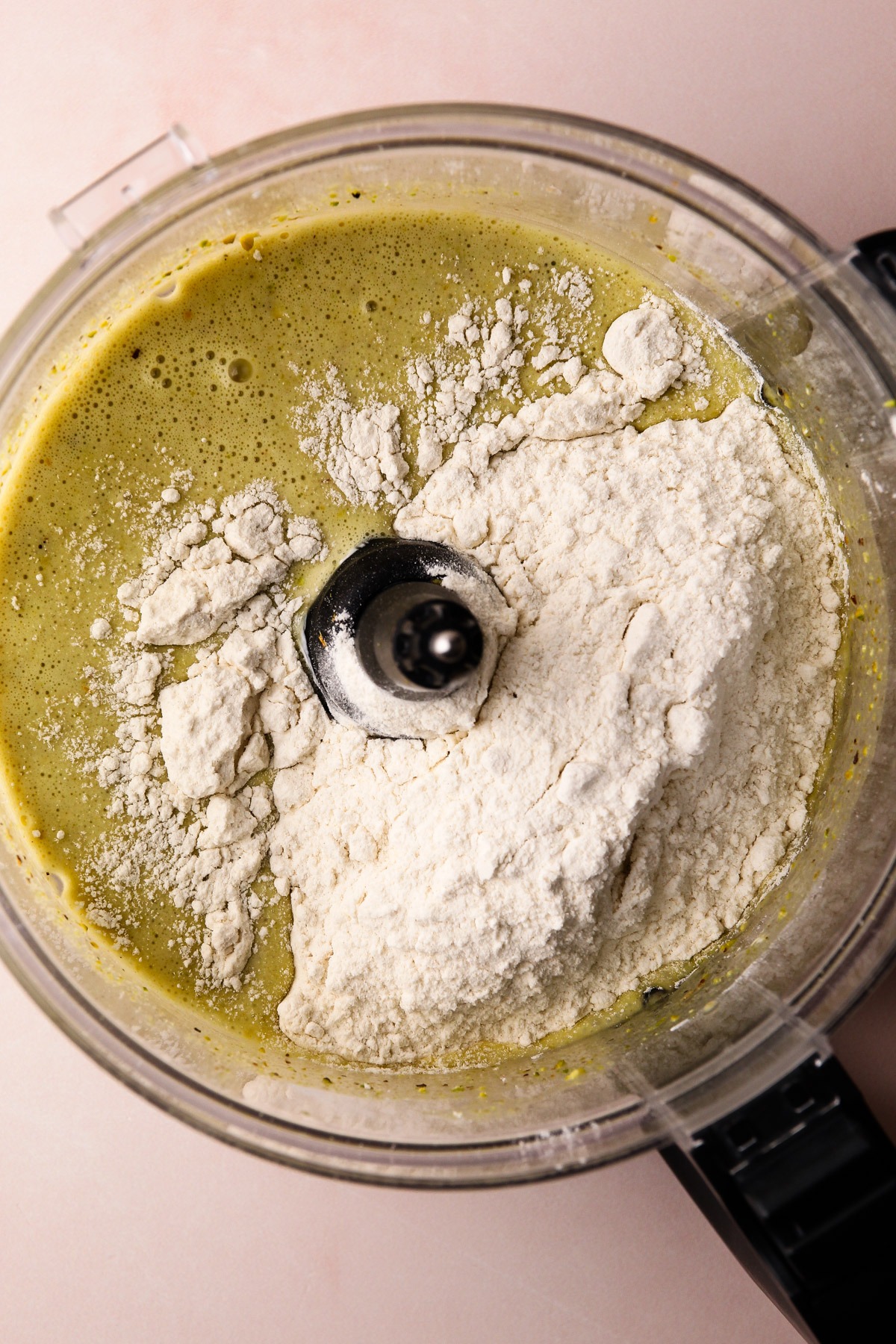 Mixing the batter for pistachio snack cake in a food processor.