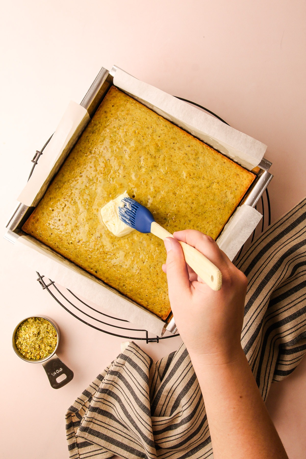 Spreading butter on the backed pistachio cake.