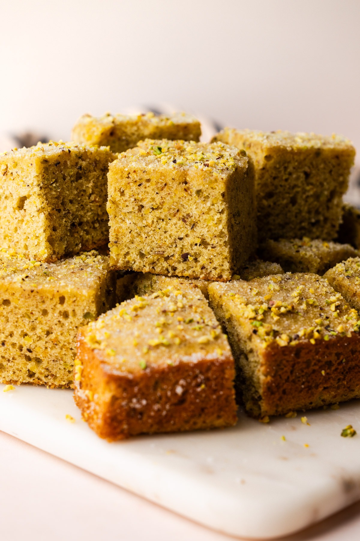 Sliced, stacked and ready to eat pistachio snack cake on a marble cutting board.