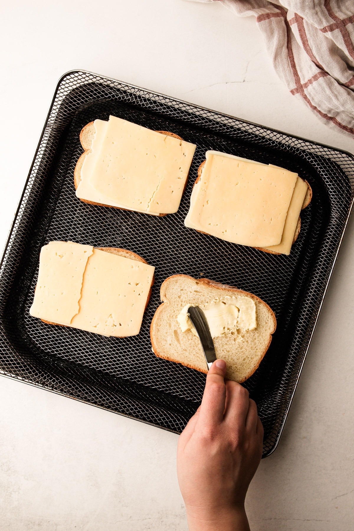 Buttering bread to make a grilled cheese in the air fryer.