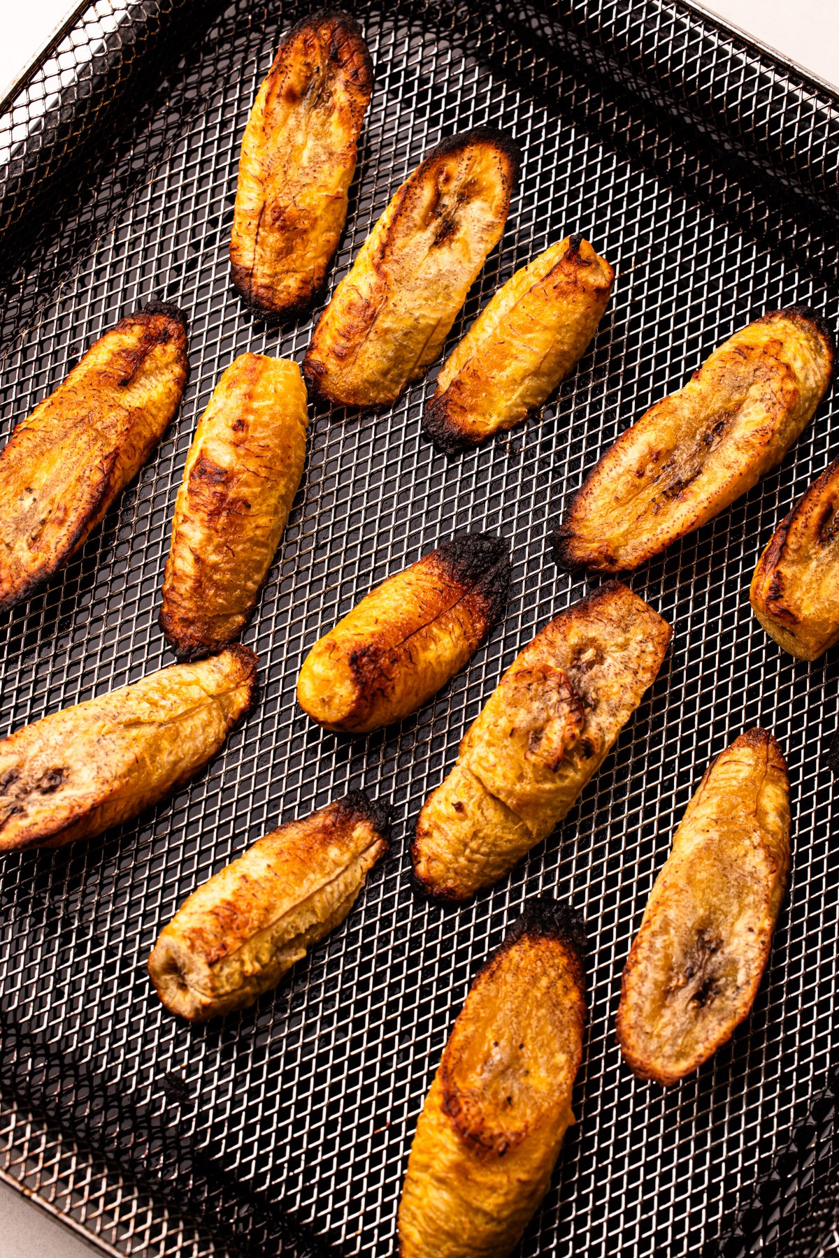 Sweet plantains sliced and cooked on an air fryer basket.