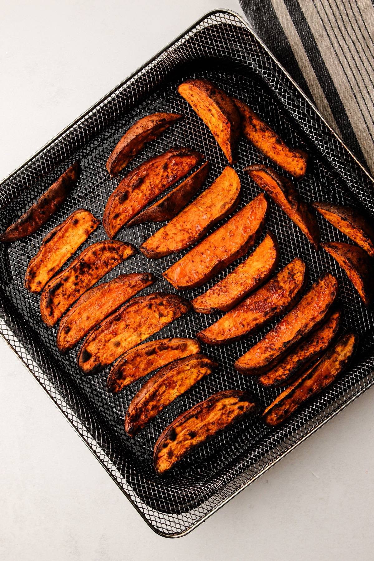 Air fryer sweet potato wedges cooked in the air fryer basket.