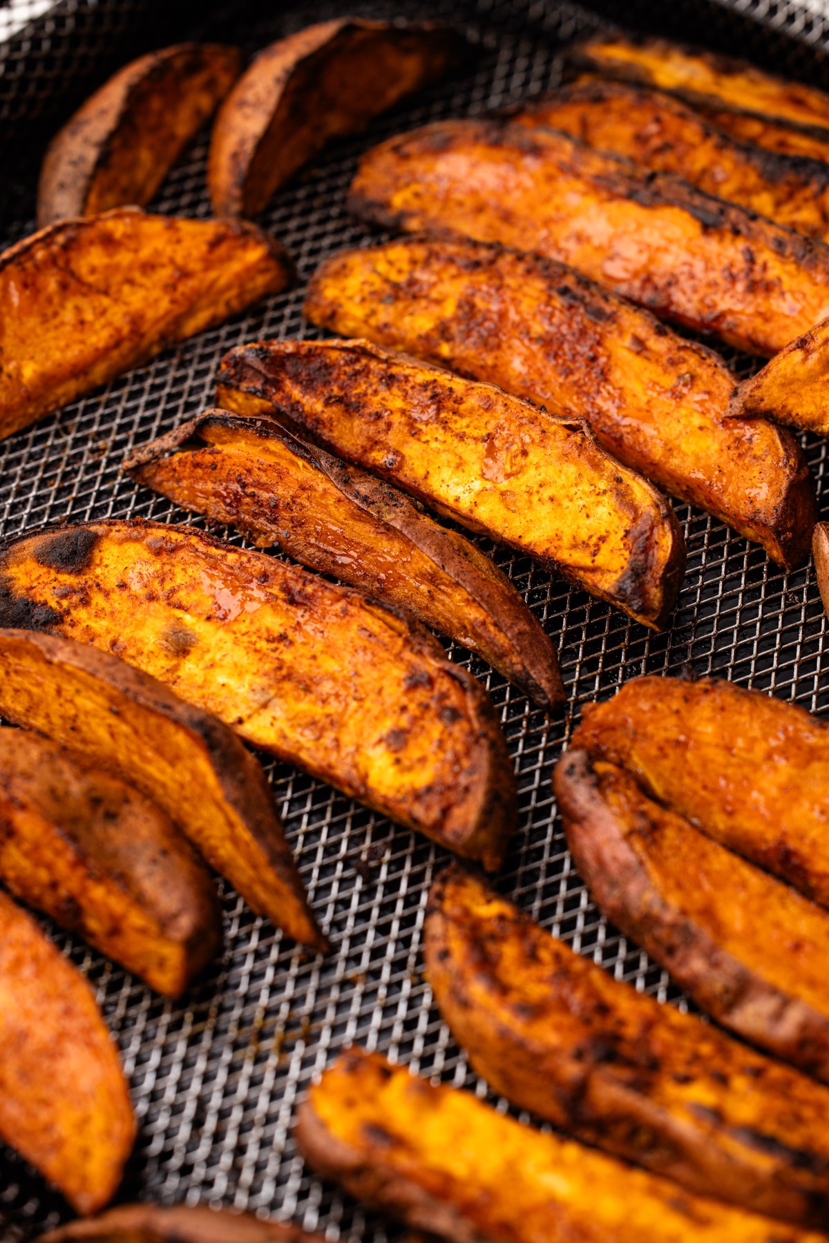 Crisp and spiced air fryer sweet potato wedges still in the air fryer basket.