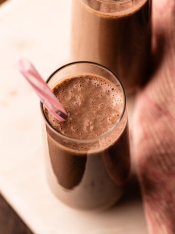 Two glasses of homemade healthy chocolate milk with a pink straw.