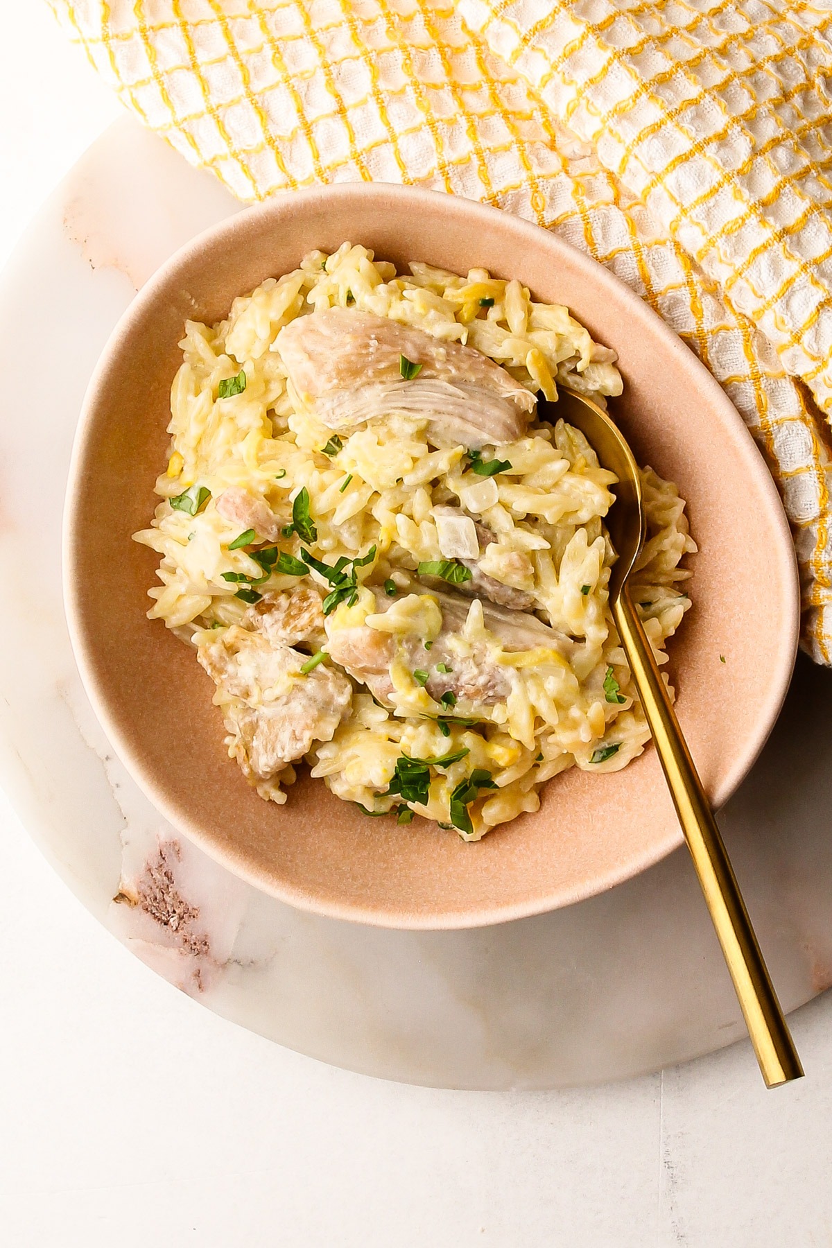 A bowl of creamy lemon chicken orzo pasta with feta and zucchini.