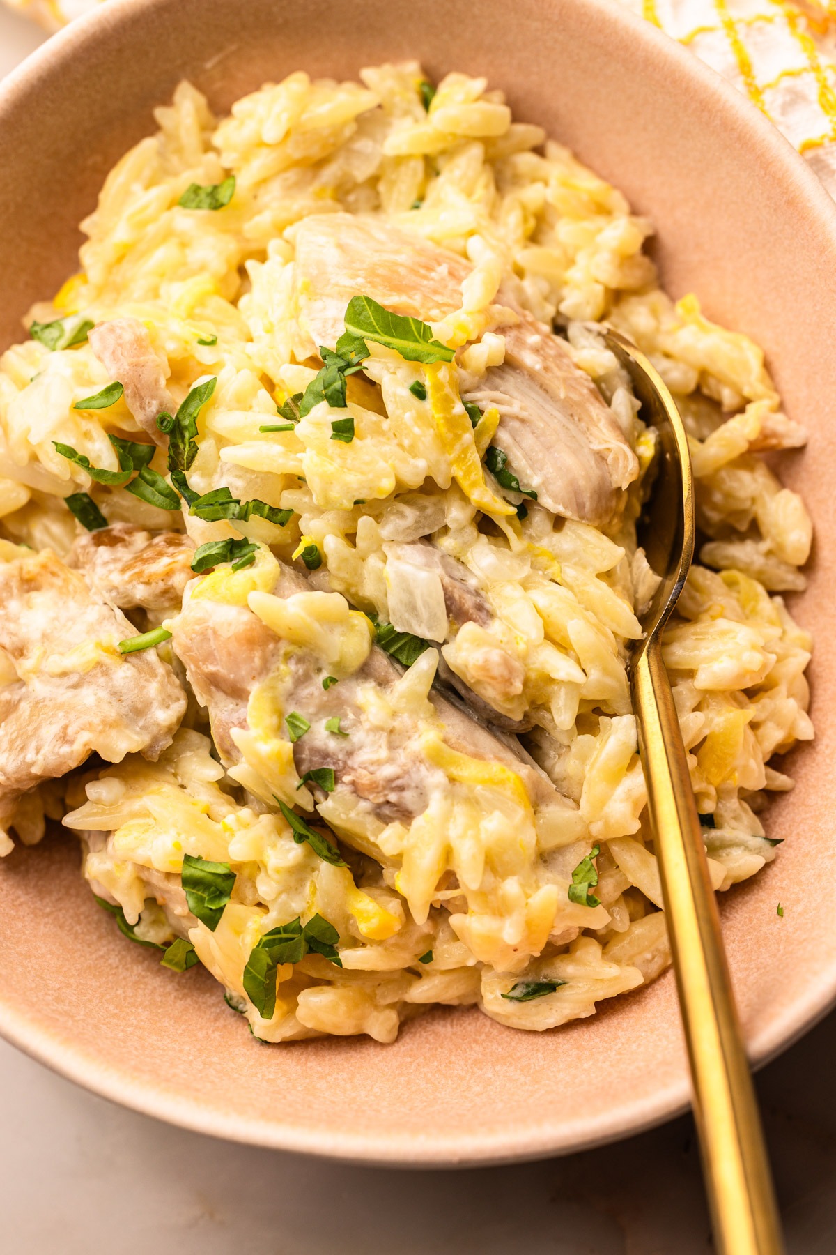 A bowl of creamy lemon chicken orzo pasta with feta and zucchini.