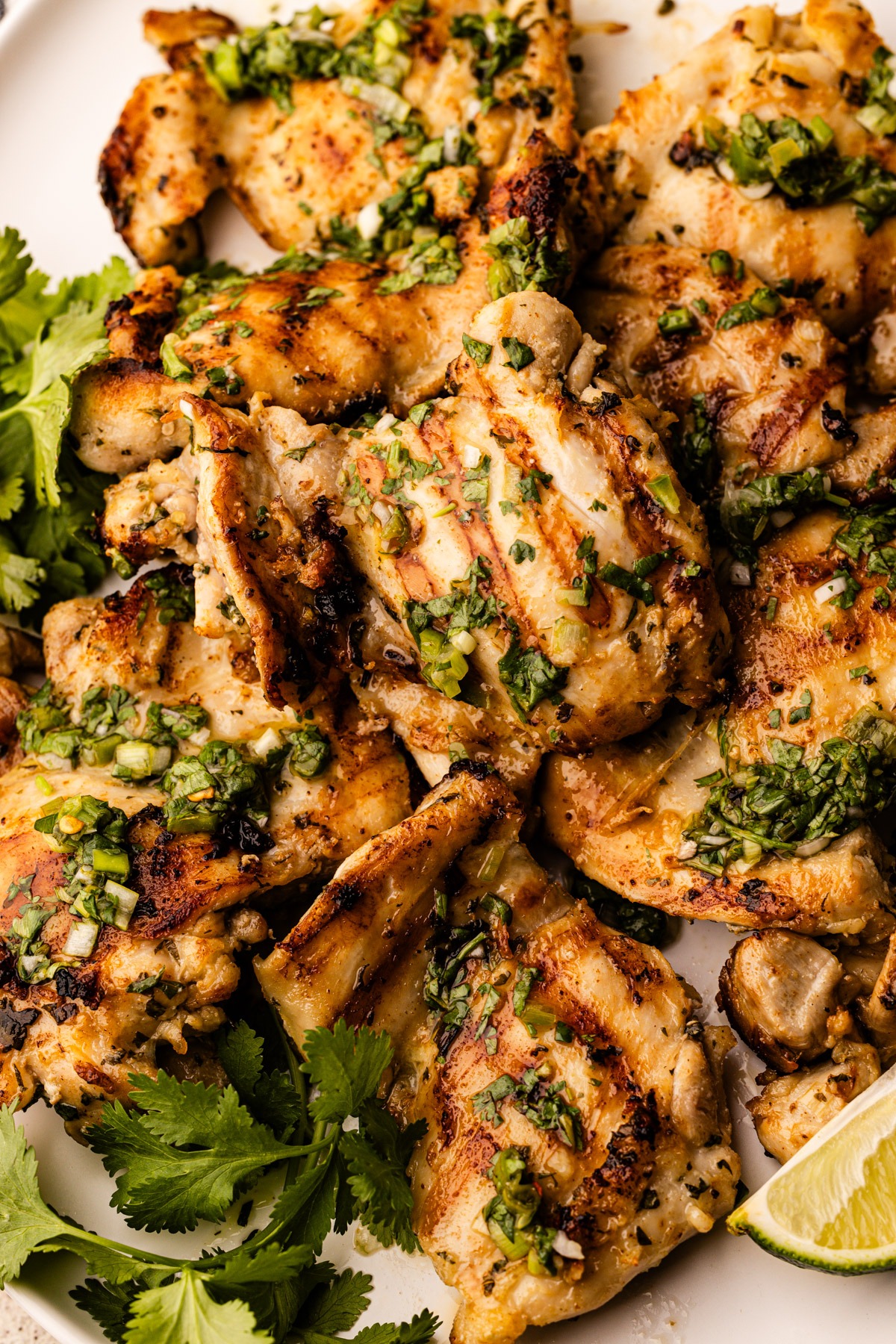 A platter of cilantro lime chicken thighs with extra cilantro and lime.