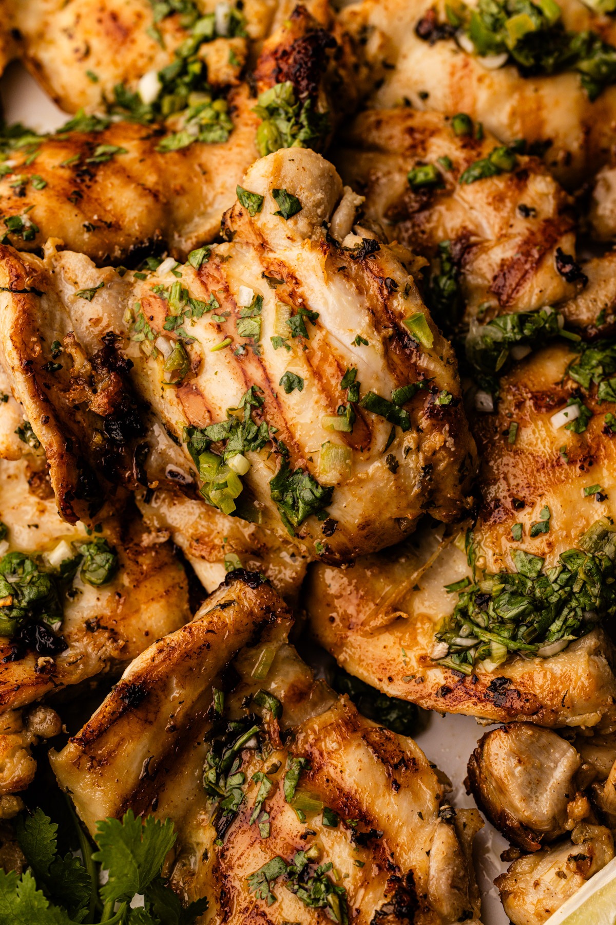 A platter of cilantro lime chicken thighs with extra cilantro and lime.