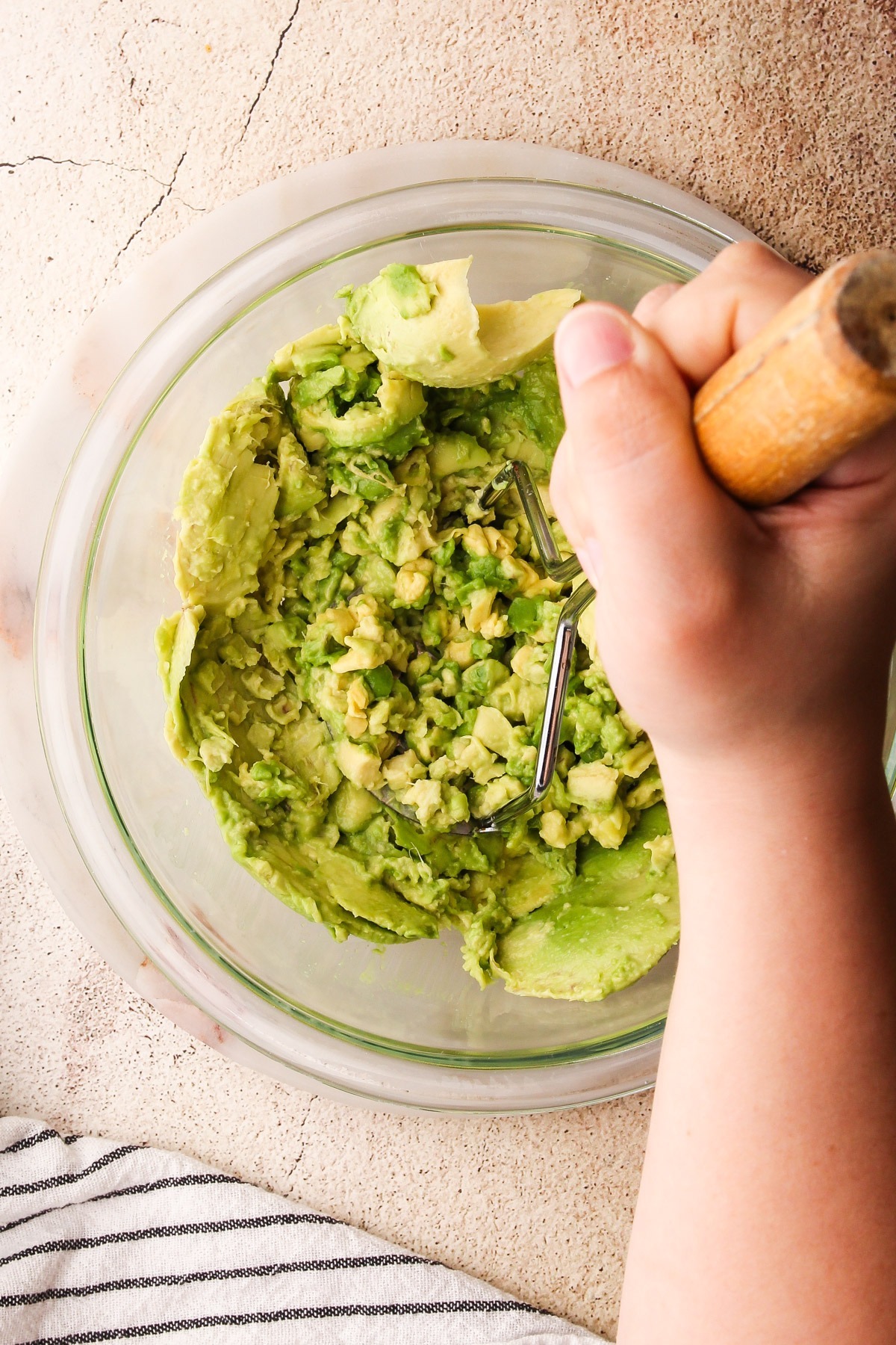 Mashing avocado in a bowl with a potato masher for guacamole.