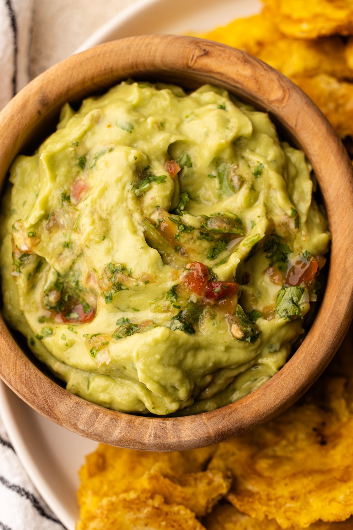 A bowl of colombian guacamole with tomatoes and cilantro.