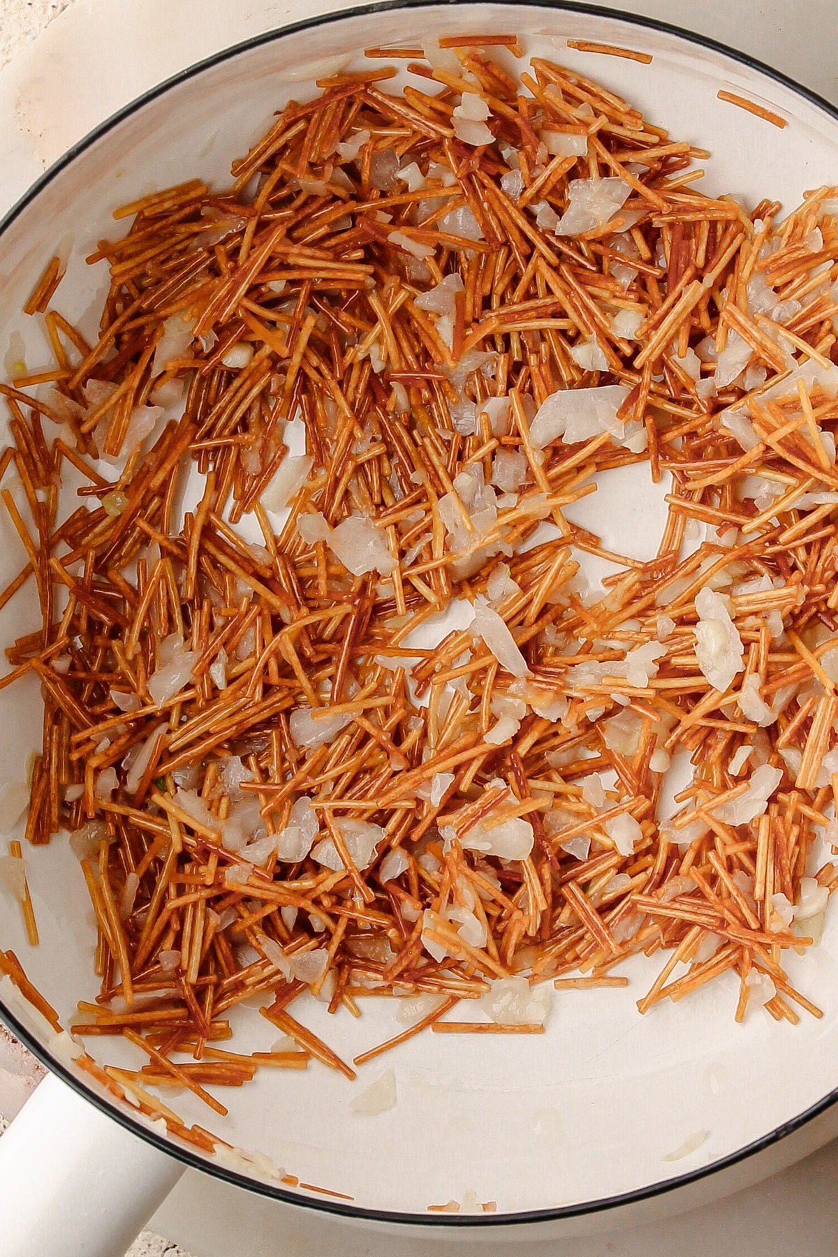 Cooking the onions and raw pasta together for a colombian rice recipe.