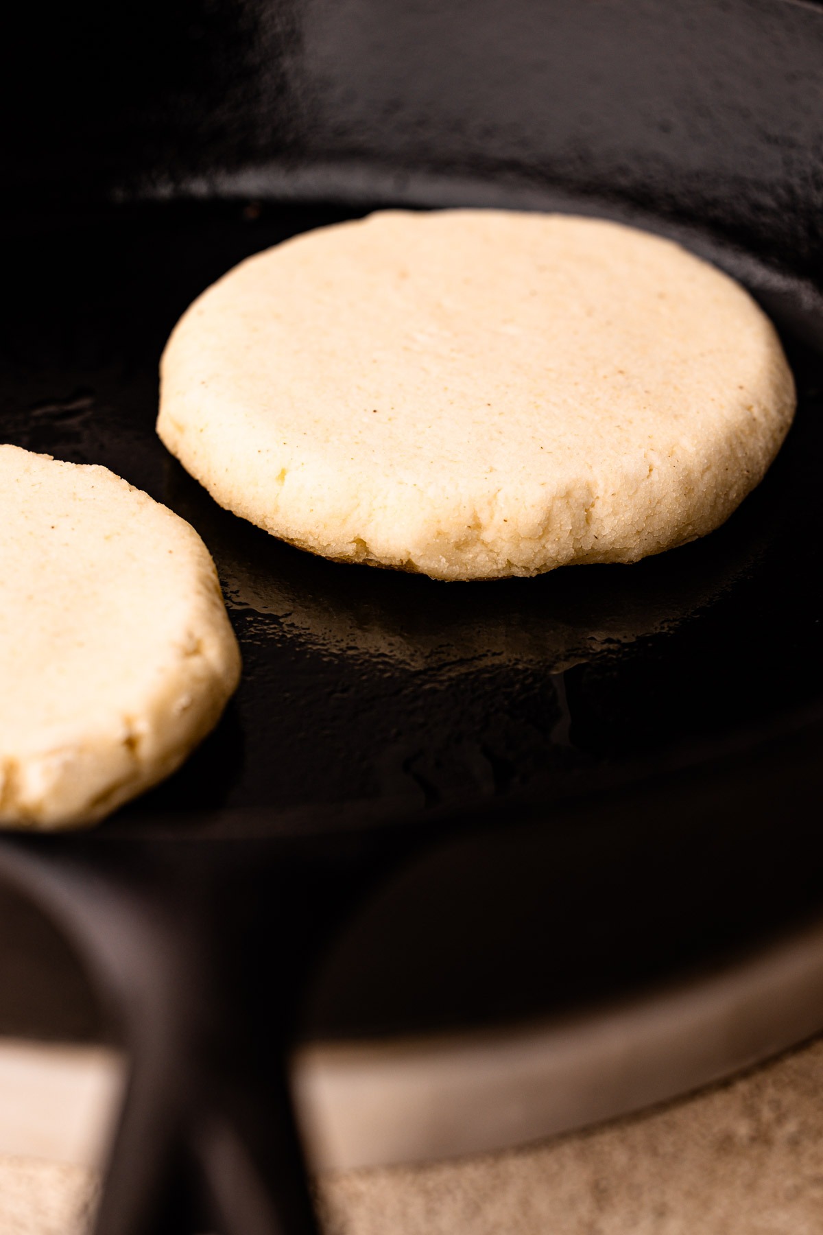 An arepa cooking in a skillet.