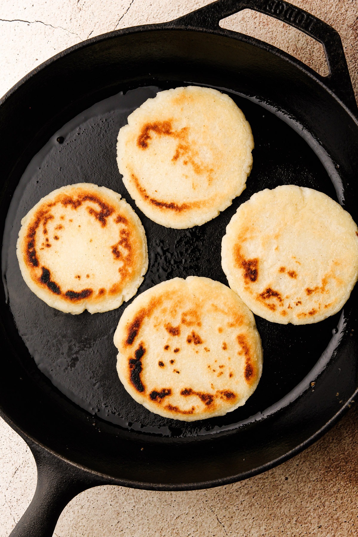 Cooking arepas in a skillet.