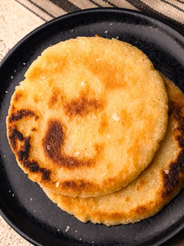 A plate of two cooked arepas.