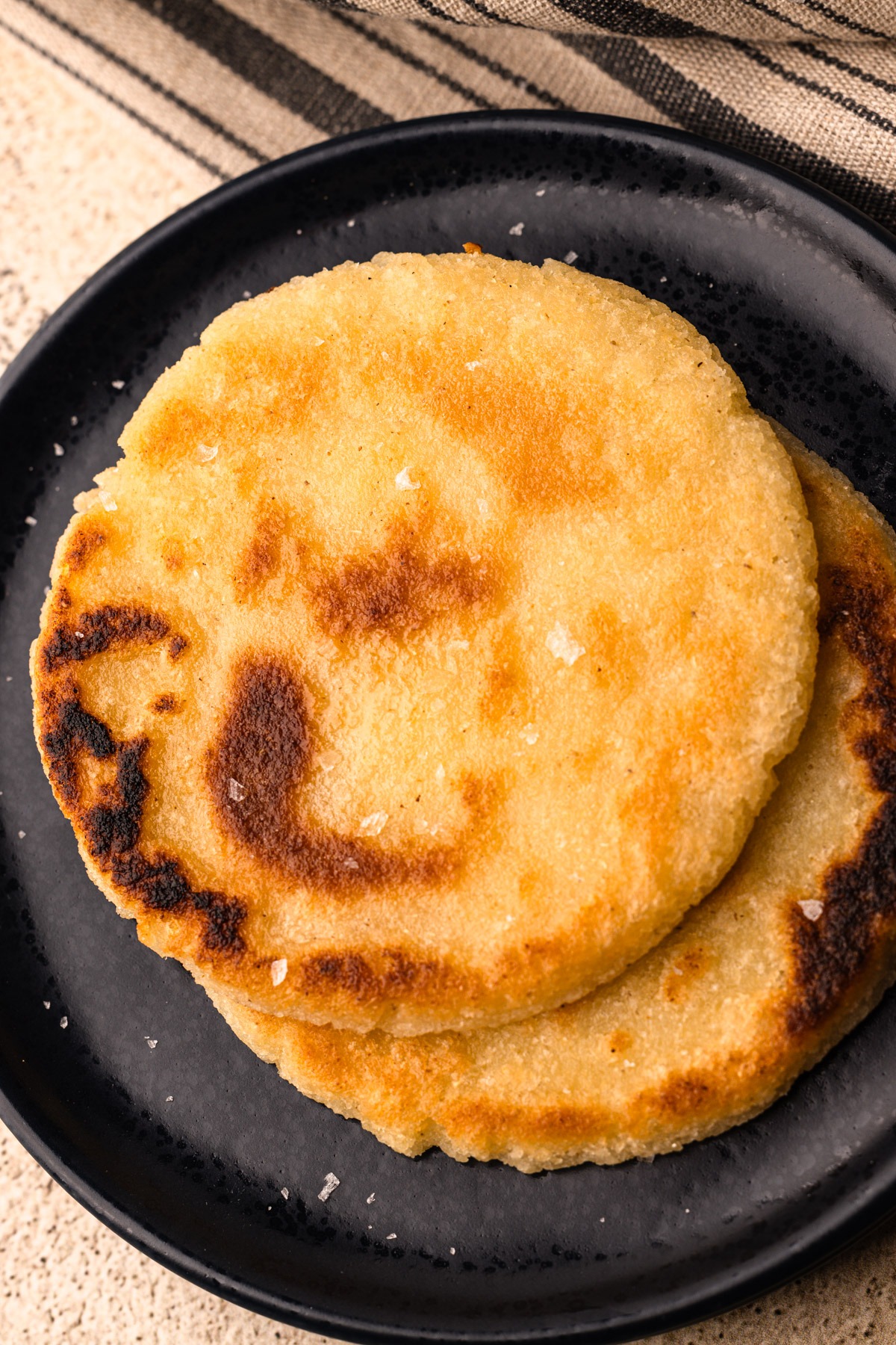 A plate of two cooked arepas.