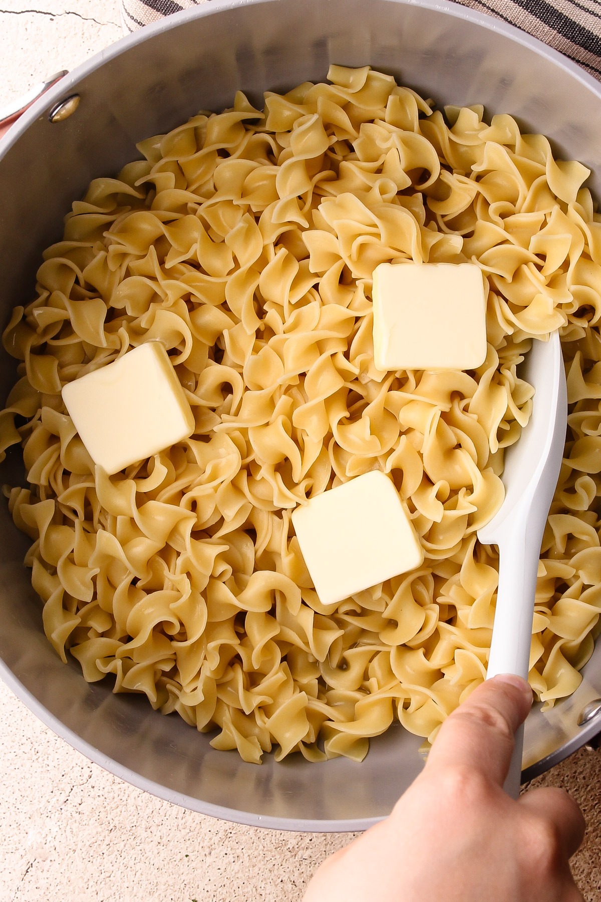 Cooked egg noodles in a pot with butter.