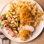 A serving plate of ritz cracker chicken with buttered egg noodles and salad.