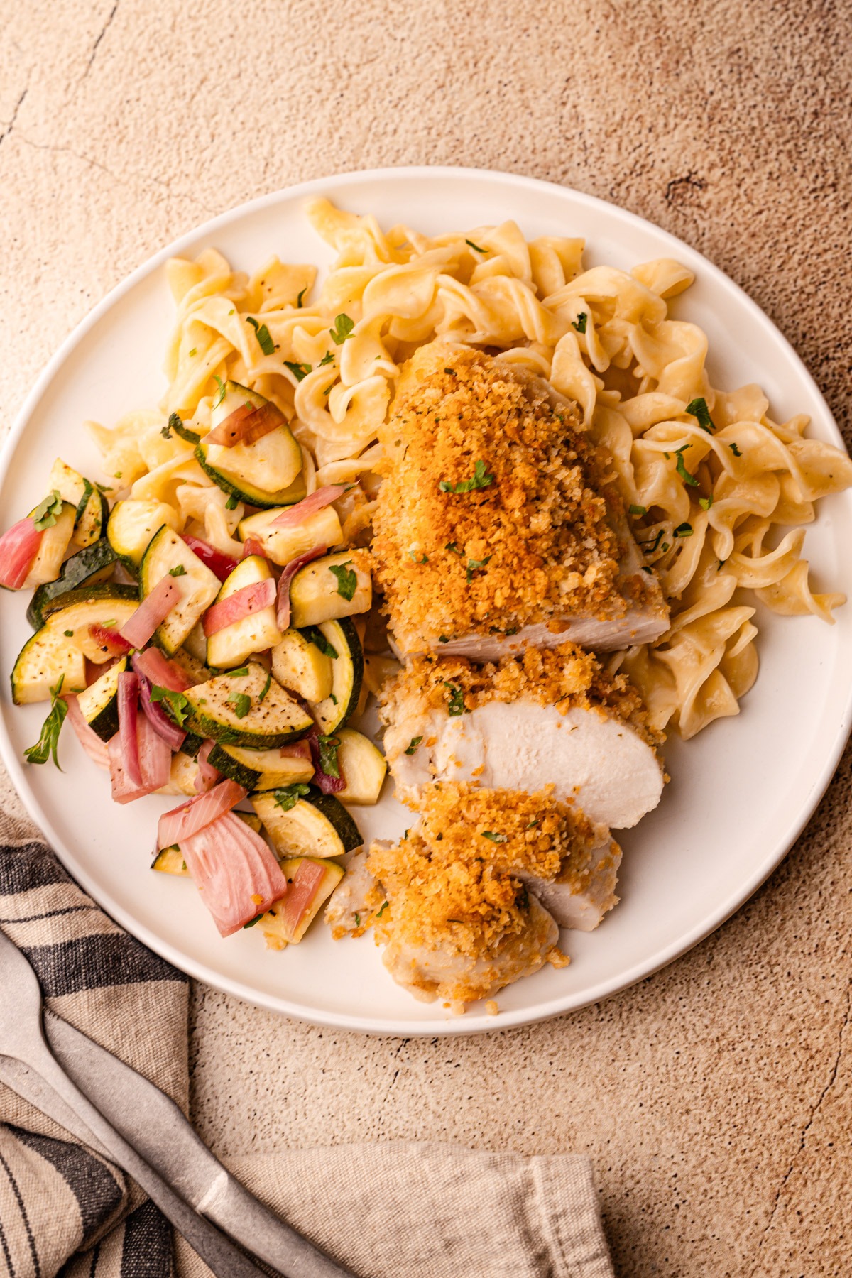 A serving plate of ritz cracker chicken with buttered egg noodles and salad.