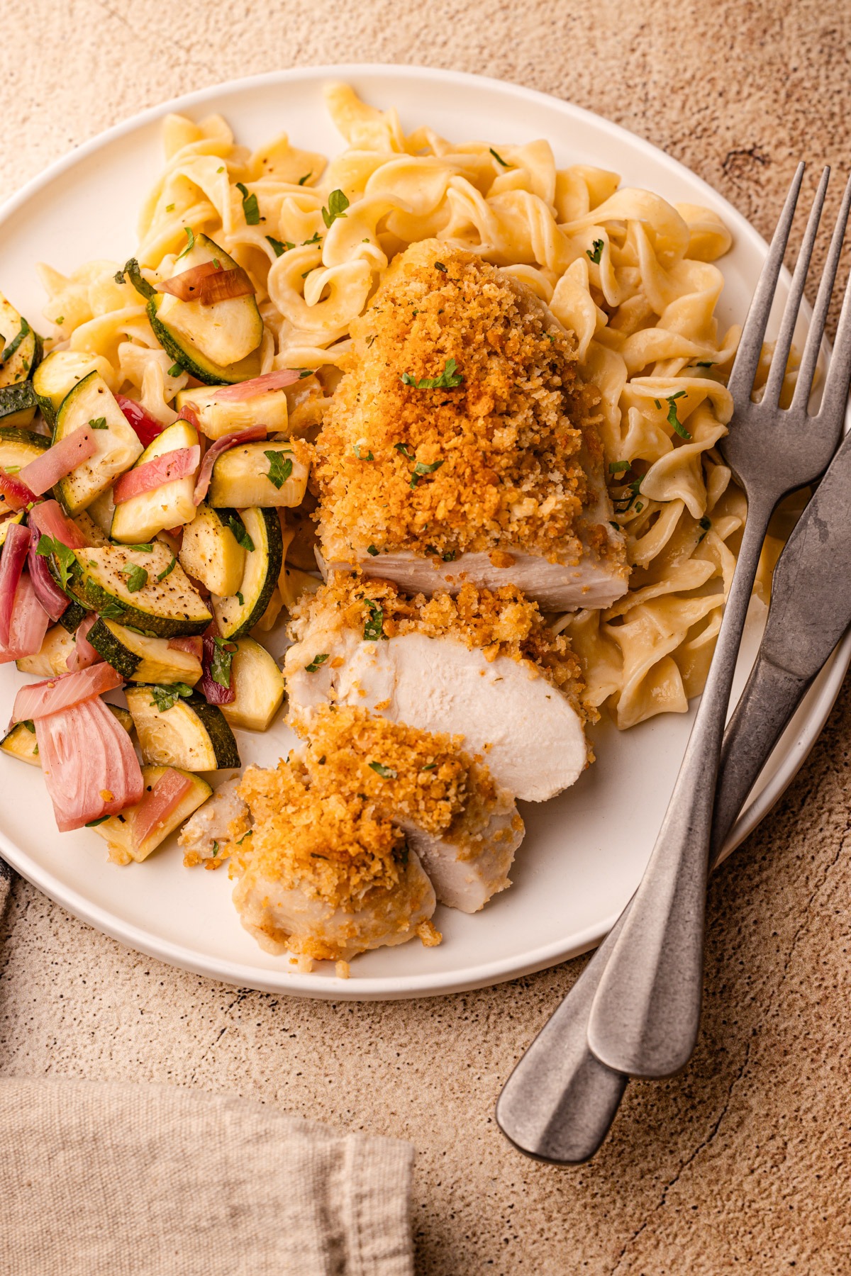 A serving plate of ritz cracker chicken with noodles and salad.