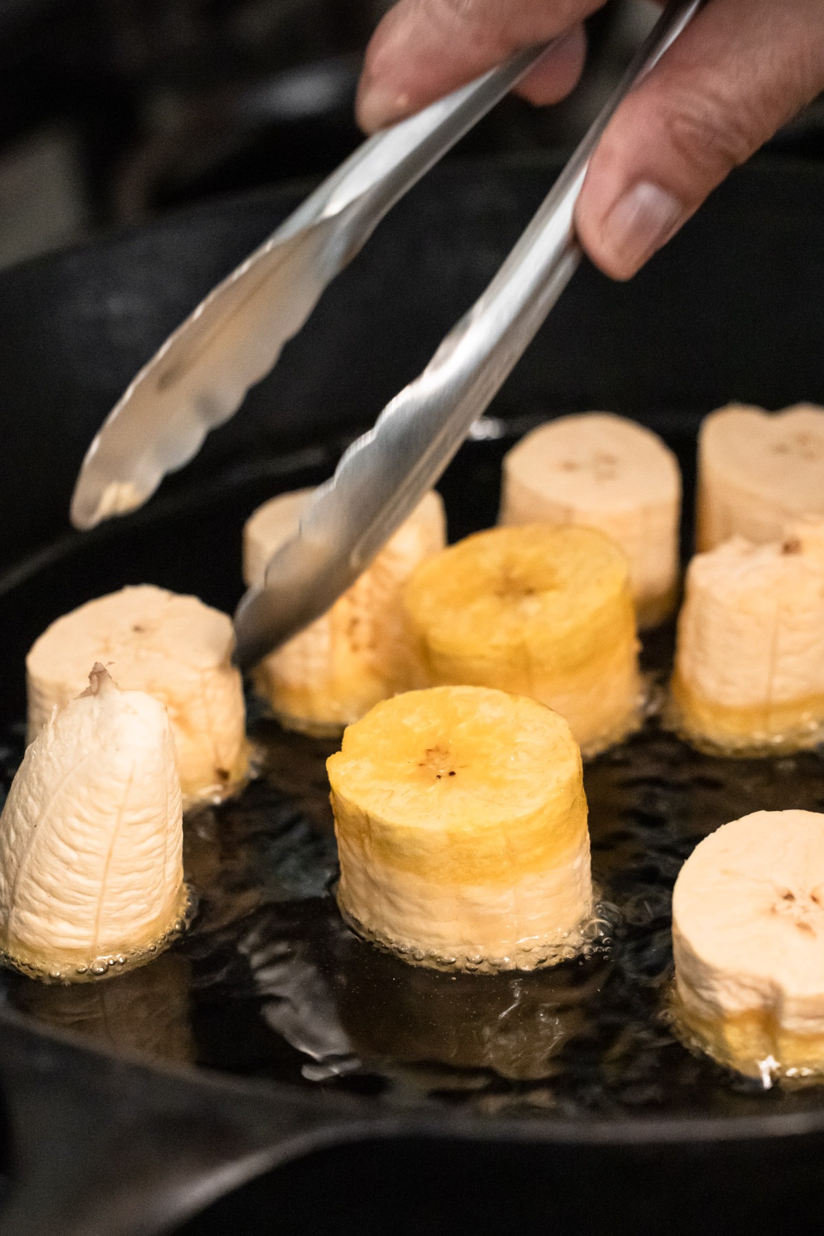 Cooking green plantains in a skillet.