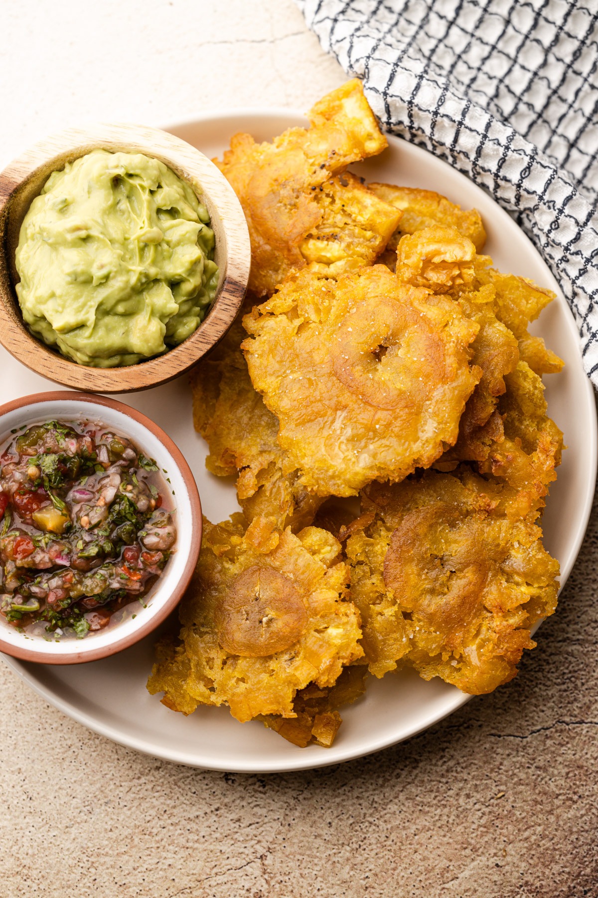 Fried green plantains on a plate with salt and dips.