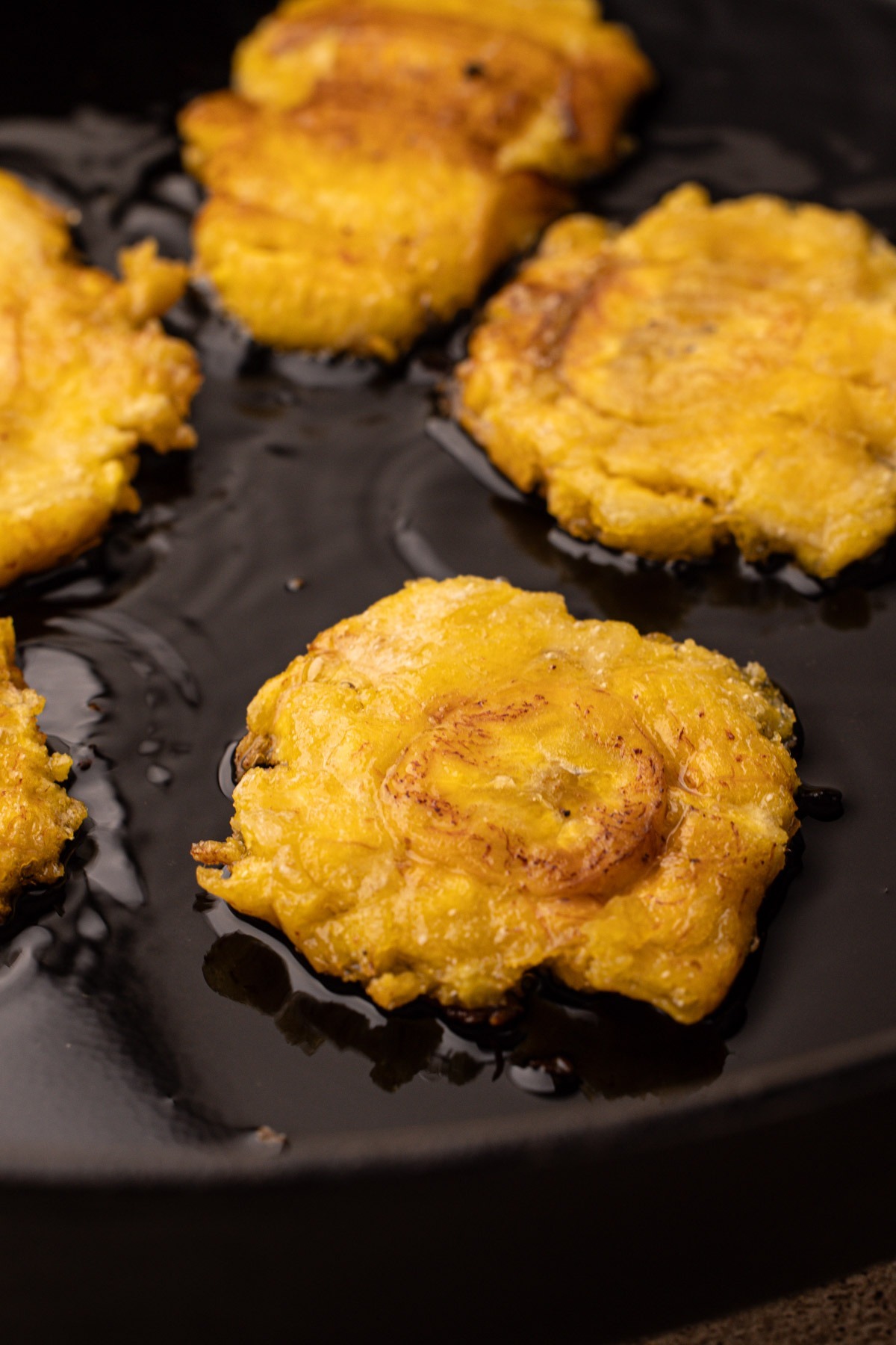 Frying green plantains for the second time in a skillet.