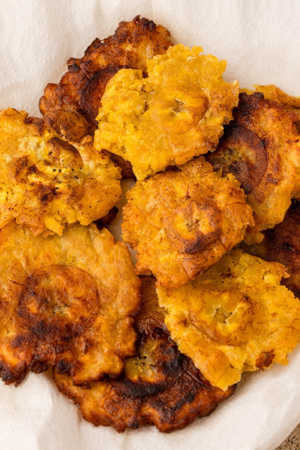 Fried green plantains draining on a paper towel.