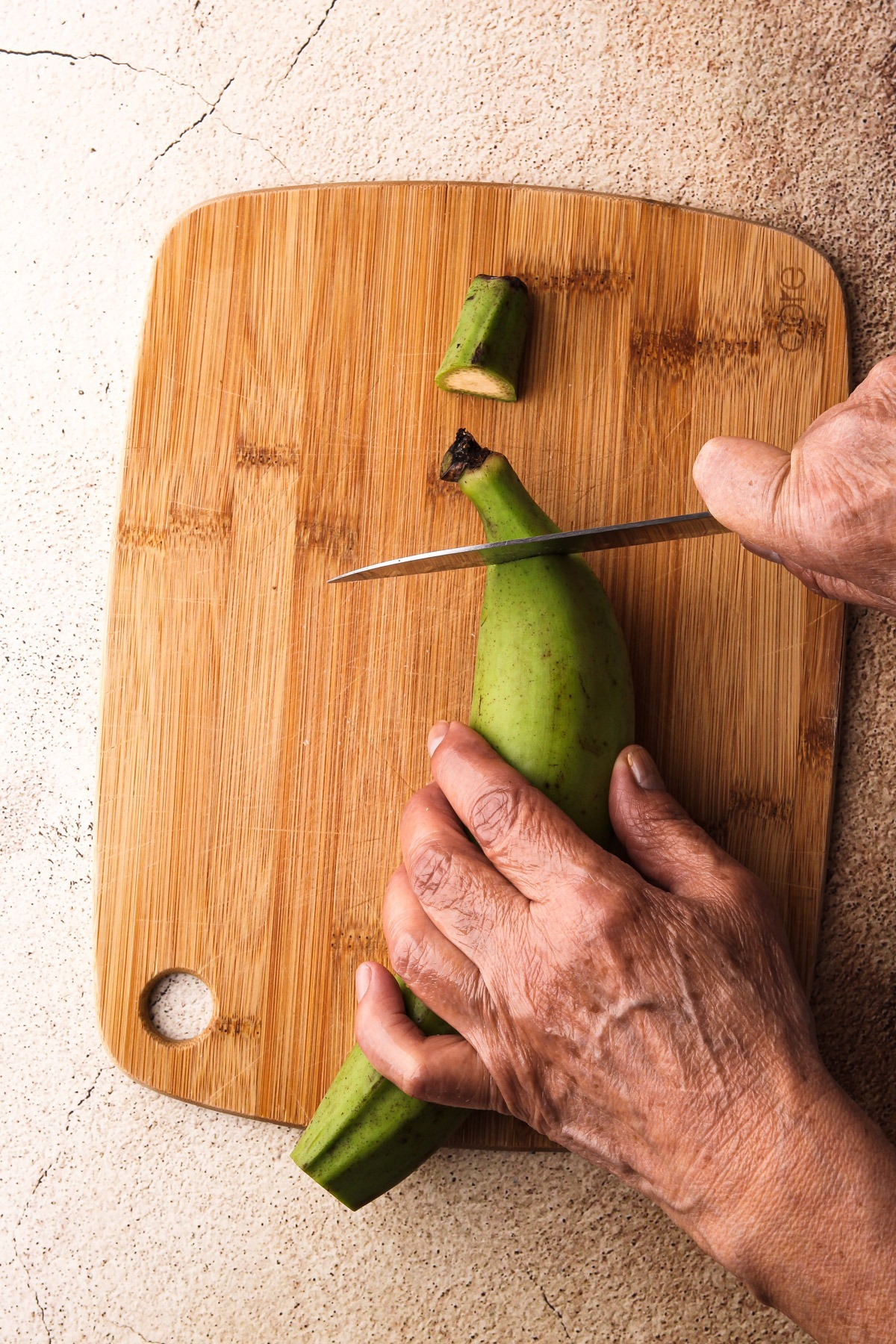 Slicing the tips off of the green plantains.