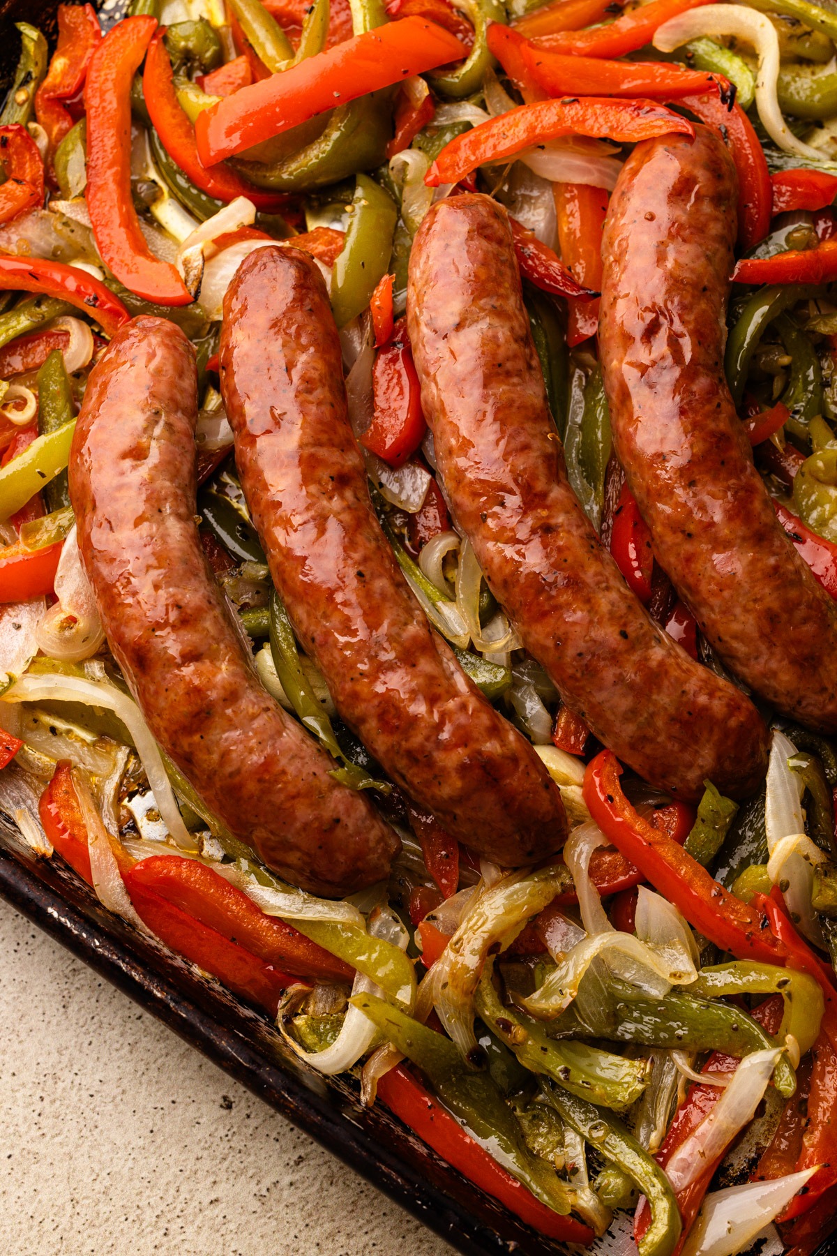 Sausage, peppers and onions cooked in the oven on a sheet pan.