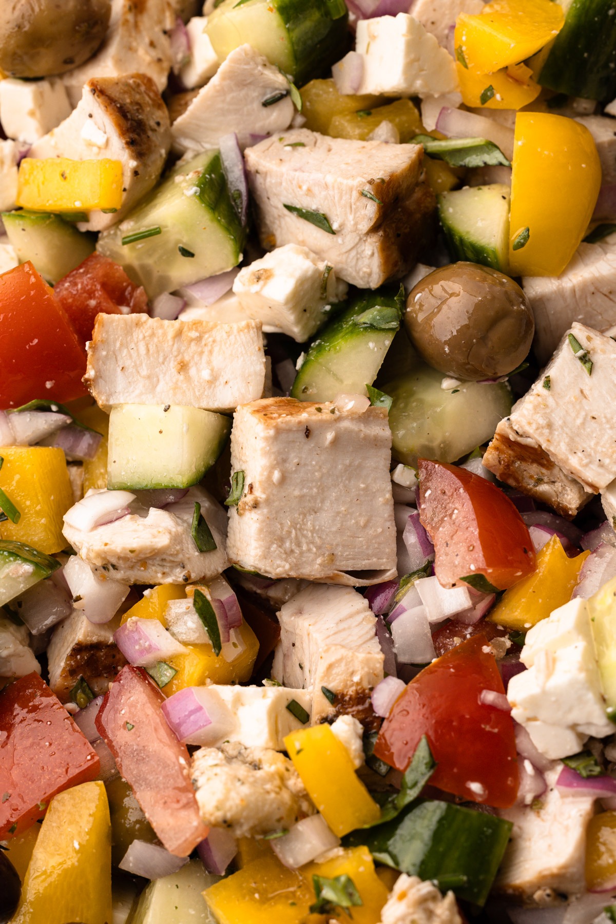 A chopped greek chicken salad with tomatoes, herbs, olives and feta.