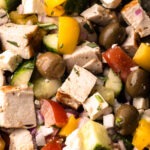 A chopped greek chicken salad with grilled chicken, olives, onions, tomatoes, and herbs.