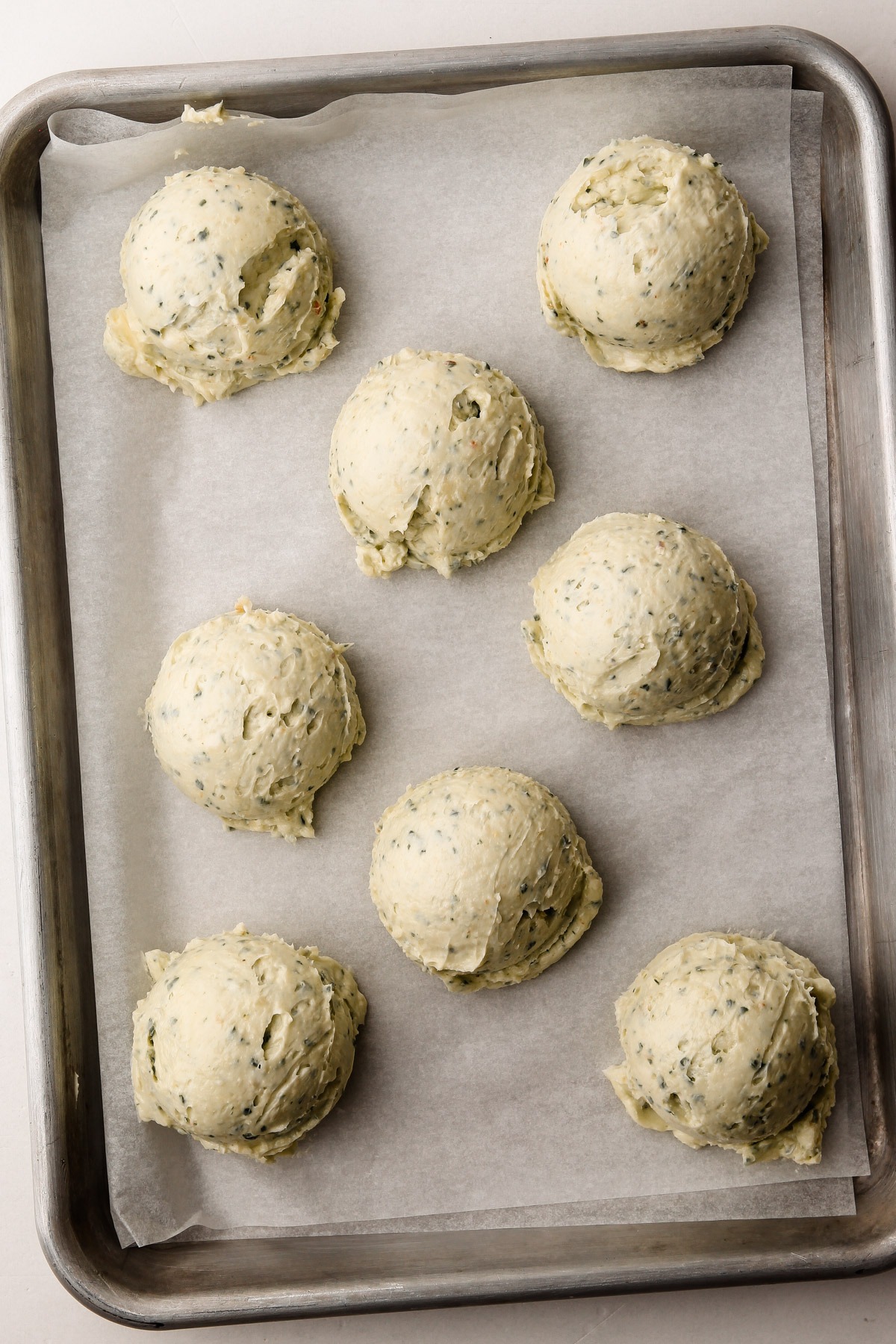 Scoops of garlic herb butter placed on a baking sheet lined with parchment paper.