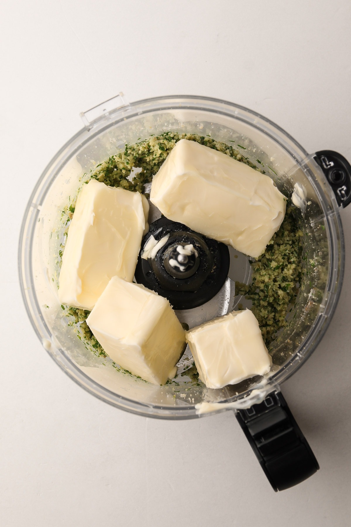 Butter added to the food processor with the blended garlic and herbs.