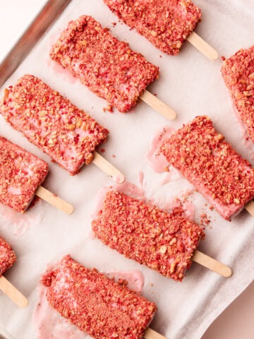 Tray of strawberry shortcake popsicles with crumbly coating, ready to be served.