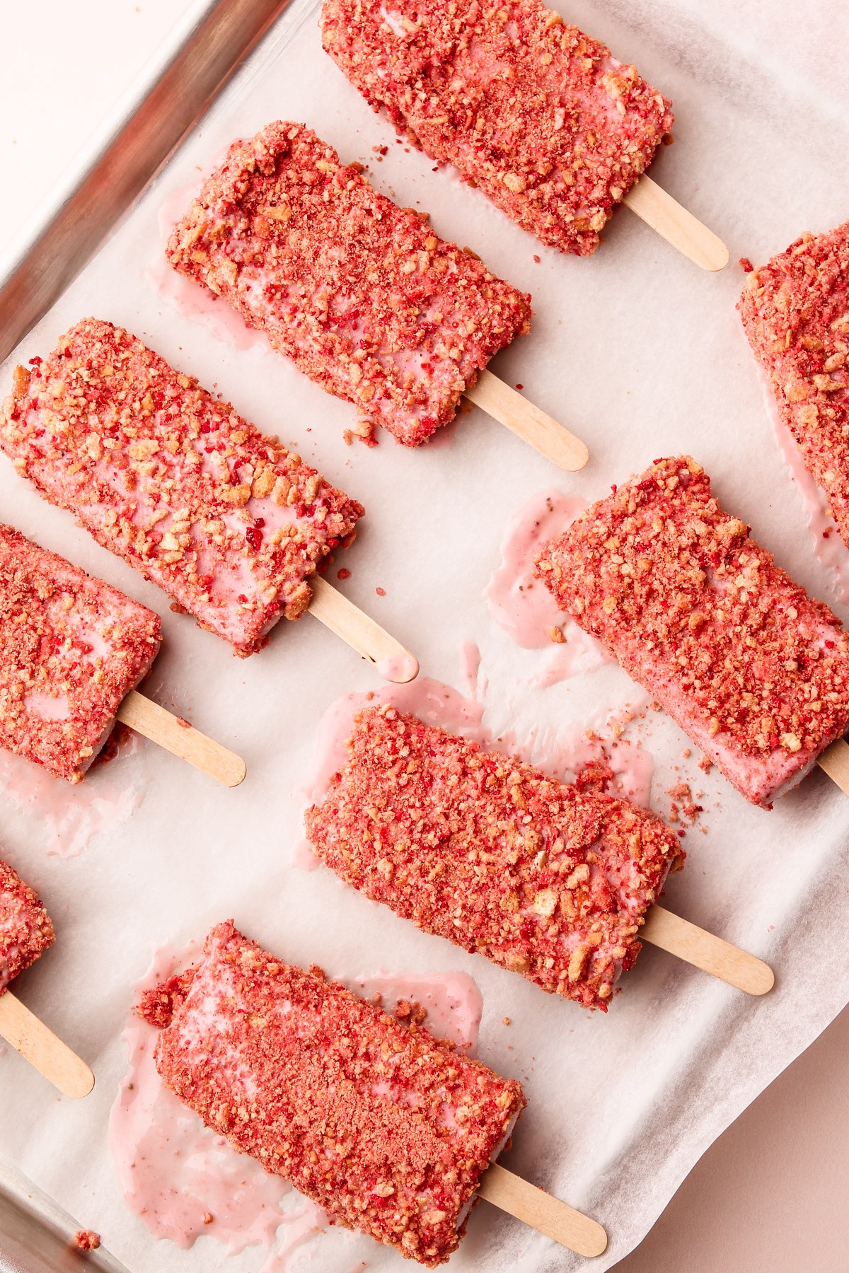 Tray of strawberry shortcake popsicles with crumbly coating, ready to be served.