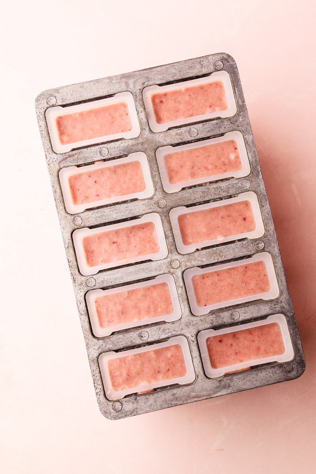 A popsicle mold filled with strawberry shortcake popsicles that aren't frozen yet.