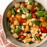 Caprese panzanella with garlic butter bread, cheese, and tomatoes, garnished with fresh basil.