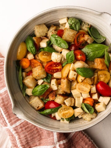 Caprese panzanella with garlic butter bread, cheese, and tomatoes, garnished with fresh basil.