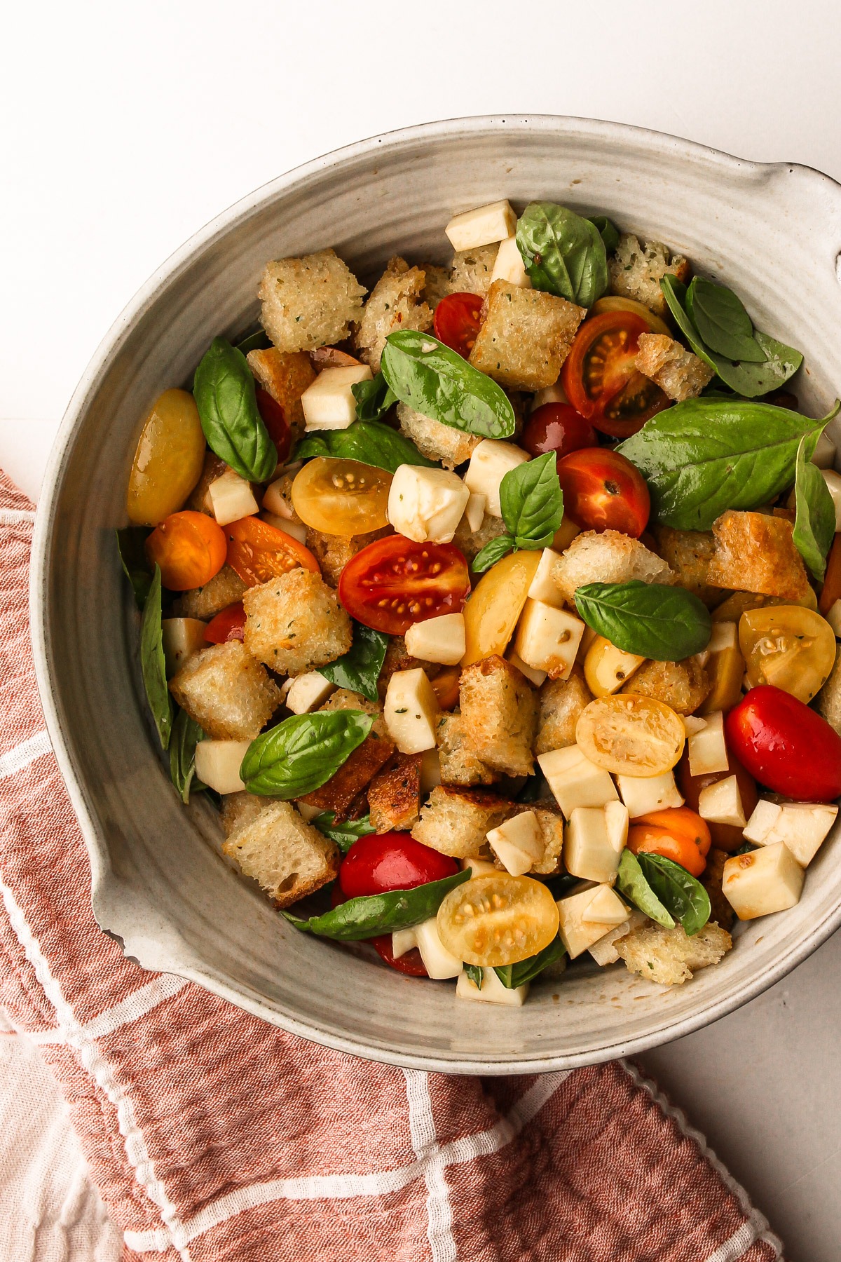 Caprese panzanella with garlic butter bread, cheese, and tomatoes, garnished with fresh basil.