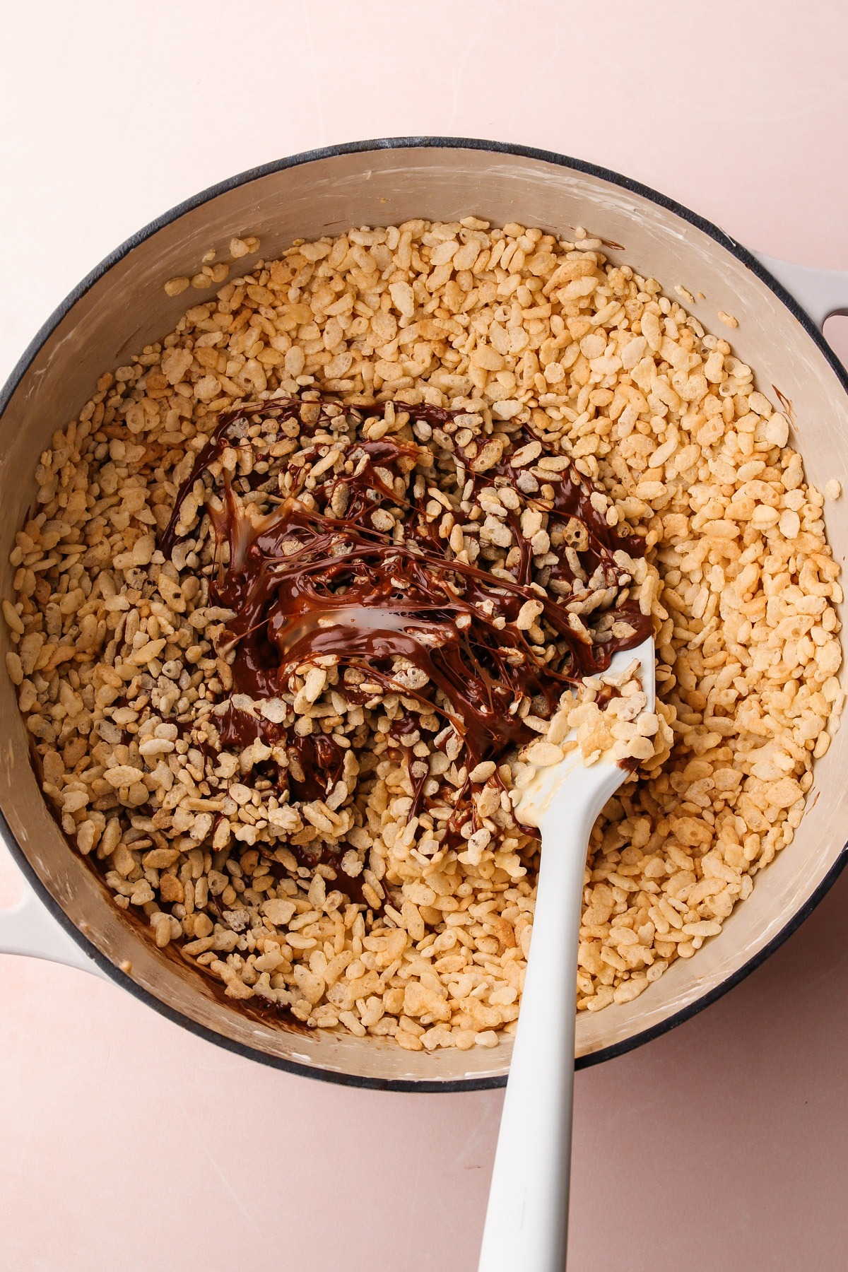 Mixing crispy rice cereal into the chocolate mixture for chocolate rice crispy treats.