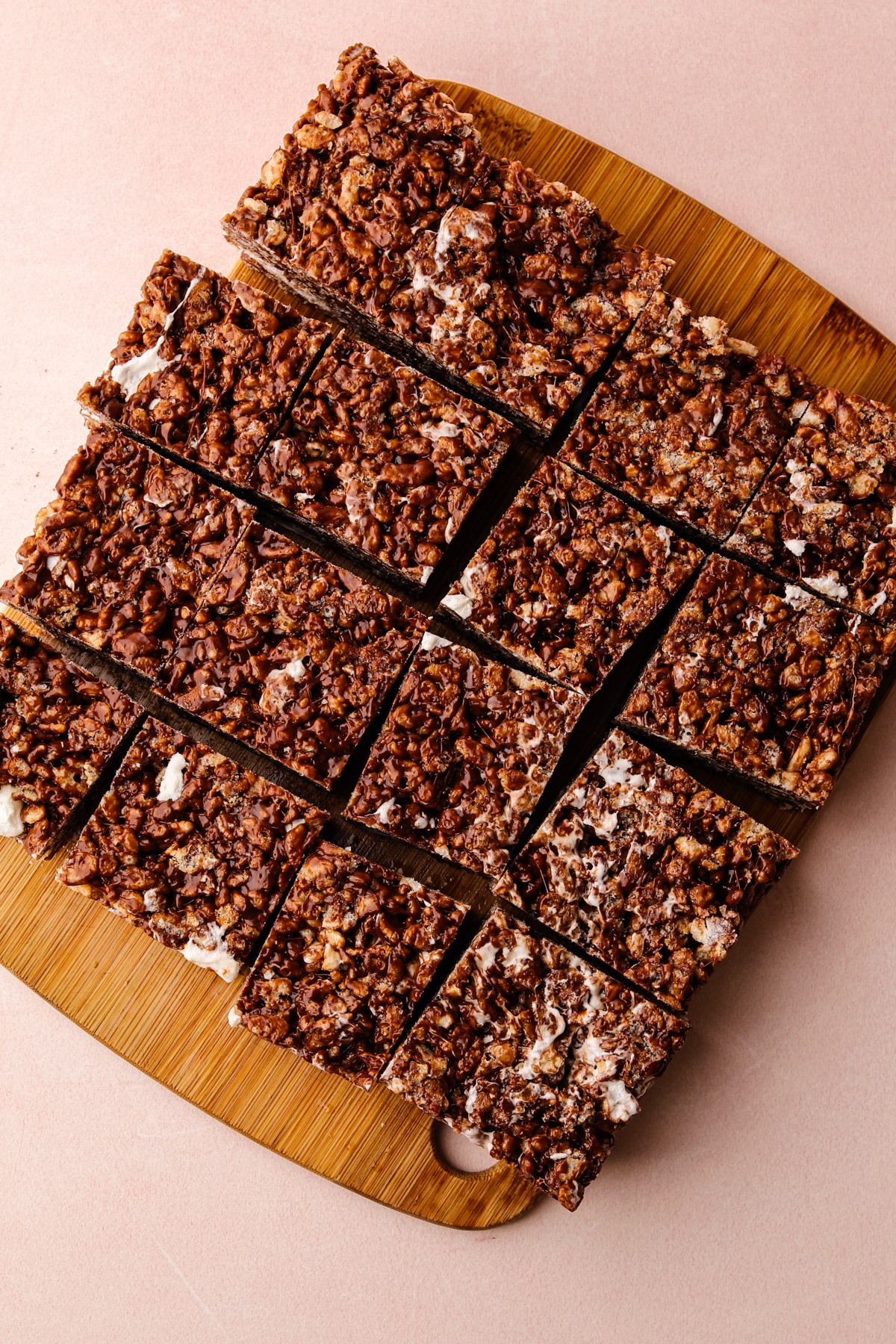 Slicing chocolate rice crispy treats into squares on a cutting board.